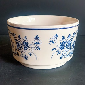 Puede incluir: Un cuenco de cer&aacute;mica blanco con un dise&ntilde;o floral azul. El cuenco tiene una forma ligeramente acampanada con una banda azul alrededor del borde. El patr&oacute;n floral se repite alrededor del exterior del cuenco.