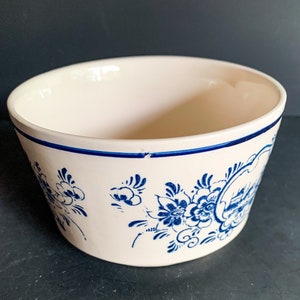 Puede incluir: Cuenco de cer&aacute;mica blanquecina con dise&ntilde;os florales y paisaj&iacute;sticos azules. El cuenco tiene un borde azul y una forma ligeramente inclinada. Los patrones florales son detallados y estilizados, a&ntilde;adiendo un toque decorativo.