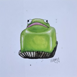 May include: A charming illustration of a green frog-shaped cake. The dessert has a glossy, light green exterior, a pink mouth, and wide-eyed expression. It rests on a brown, fluted paper cup, with the artist's signature in the bottom right corner.
