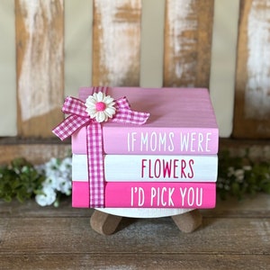 May include: Three pink and white stacked wooden blocks with the text "If moms were flowers I'd pick you" in pink lettering. The top block has a pink and white gingham ribbon with a white daisy.