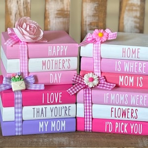 May include: A stack of pink and white wooden blocks with pink and white gingham ribbon. The blocks have the following text: "Happy Mother's Day", "I Love That You're My Mom", "Home Is Where Mom Is", "If Moms Were Flowers I'd Pick You".