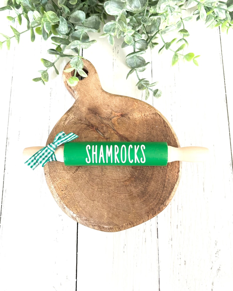 May include: Green rolling pin with a white "Shamrocks" inscription on a wooden chopping board.