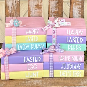 以下が含まれることがあります： パステルカラーのウッドブロックの積み重ねで、イースターをテーマにした言葉が書かれています。ブロックはパステルカラーのリボンとボウで飾られています。ブロックに書かれている言葉は、「ハッピーイースター」、「エブリバニー」、「イースターエッグハント」、「ハッピーイースターディーズ」、「イースターバニージェリービーンズ」、「イースターエッグ」です。