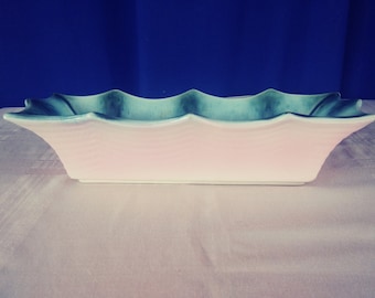 May include: A rectangular ceramic planter with a light pink interior and a wavy, light blue and green exterior.