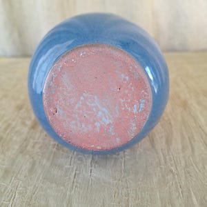 May include: The bottom of a light blue ceramic vase with a brown unglazed base.
