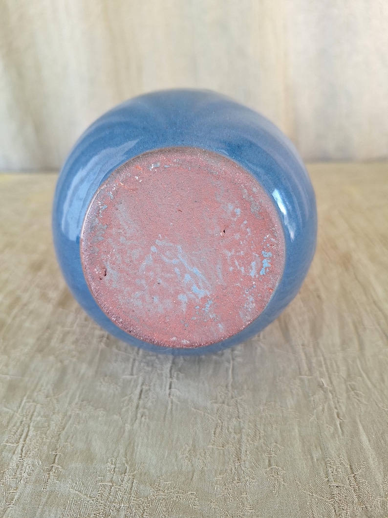 May include: The bottom of a light blue ceramic vase with a brown unglazed base.