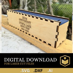 May include: A wooden box with a blue interior and laser-cut joinery. The box is engraved with "10TH ANNIVERSARY UTOPIA LAKE BOYS TRIP 2015-2025". The image also includes the text "DIGITAL DOWNLOAD FOR LASER CUT FILES .SVG .DXF .AI".