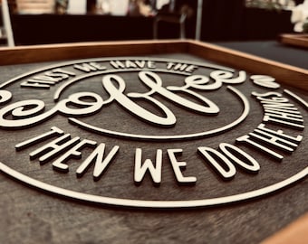 May include: A wooden sign with a circular design featuring the text "First we have the coffee then we do the things". The words are in white raised lettering on a dark brown background.