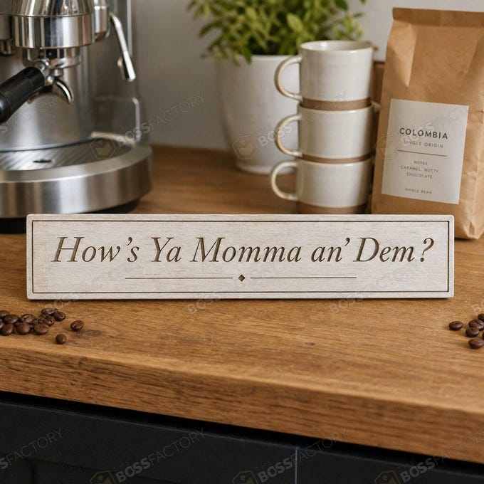 Laser-engraved solid pine coffee bar sign shown in Linen White stain with the phrase “How’s Ya Momma an’ Dem?” for Southern kitchen decor.