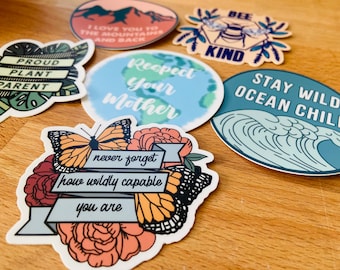 Könnte beinhalten: Eine Sammlung farbenfroher Aufkleber mit verschiedenen Designs und Texten. Ein Aufkleber trägt die Aufschrift "Proud Plant Parent", ein anderer "Respect Your Mother" und ein dritter "Stay Wild Ocean Child". Weitere Aufkleber zeigen eine Biene, einen Schmetterling und eine Berglandschaft.