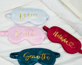 May include: Four personalized sleep masks in different colors. The masks are made of satin and have gold lettering. The names on the masks are Lauren, Caroline, Natasha, and Samantha.