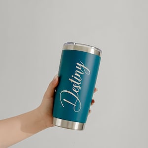 May include: Teal insulated tumbler with a silver rim and lid. The word "Destiny" is written in a cursive font on the side of the tumbler. The tumbler is cylindrical and appears to be made of stainless steel.