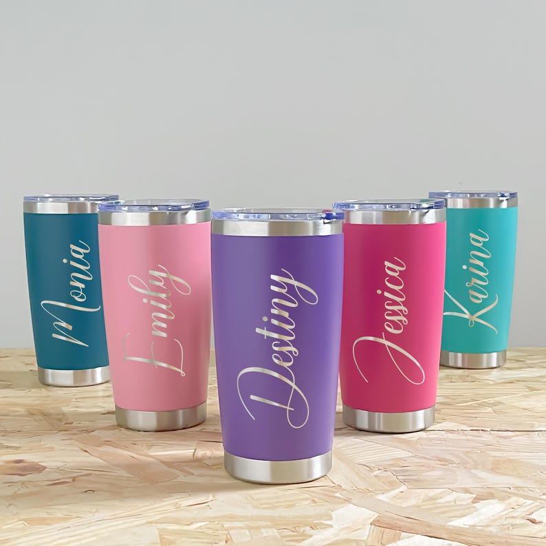 May include: A collection of five stainless steel tumblers in various colors: teal, pink, purple, magenta, and turquoise. Each tumbler has a silver base and lid, with a name in cursive script. The names are Monia, Emily, Destiny, Jessica, and Karina.