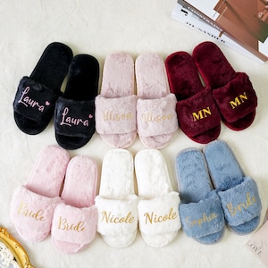 May include: Set of ten fuzzy slippers with personalized names and the word "Bride" embroidered in gold. The slippers are in various colors, including black, pink, white, red, and blue.