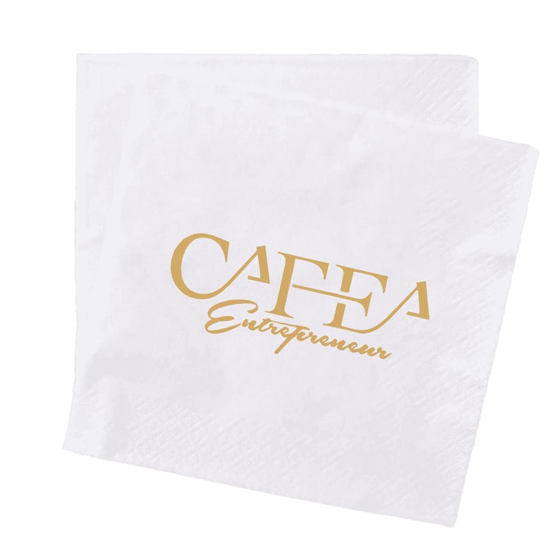 May include: White paper napkins with a subtle textured pattern. The napkins feature the gold text "CAFFA Entrepreneur" in a stylized font. The napkins are folded and appear clean and unused, suitable for events or dining.