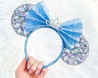 Op de afbeelding: Lichtblauwe glinsterende Minnie Mouse oren met een zilveren kroon en iriserende strass steentjes.
