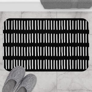 May include: Black and white bath mat with a repeating pattern of white lines on a black background.
