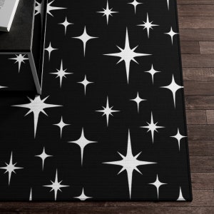 May include: Black and white area rug with a repeating pattern of white starbursts on a black background.