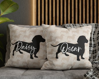 May include: Two beige throw pillows with black dachshund silhouettes and the names "Daisy" and "Oscar" printed in white.