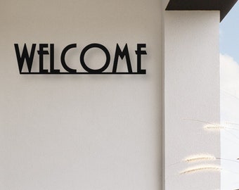 May include: Black metal "WELCOME" sign mounted on a white wall.