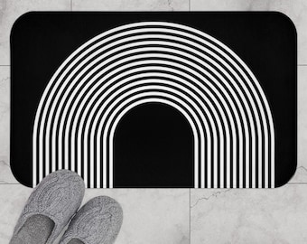 May include: Black and white striped bath mat with a rainbow arch design. The mat is made of a soft, absorbent material and is perfect for adding a touch of style to any bathroom.