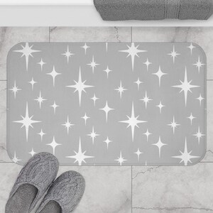 May include: A gray bath mat with a white star pattern. The mat is made of a soft, absorbent material and is perfect for adding a touch of style to any bathroom.