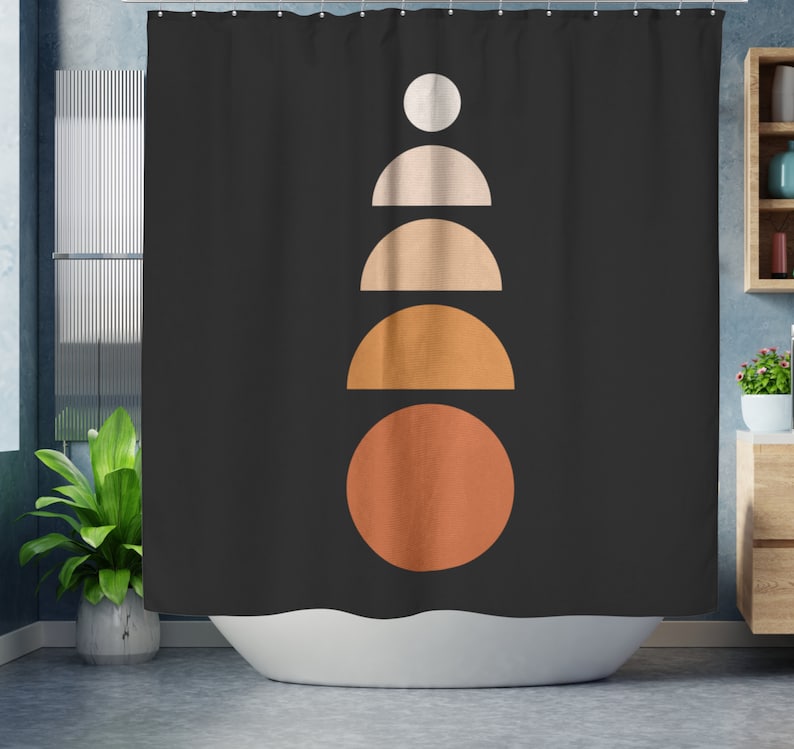 May include: Black shower curtain with a geometric design. The design features a stack of shapes in white, beige, and orange hues. The shapes include a circle, semi-circles, and a full circle. The curtain is hanging in a bathroom setting.