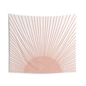 May include: A pink and white tapestry with a sunburst design. The sun is a solid pink circle with white rays emanating from it.