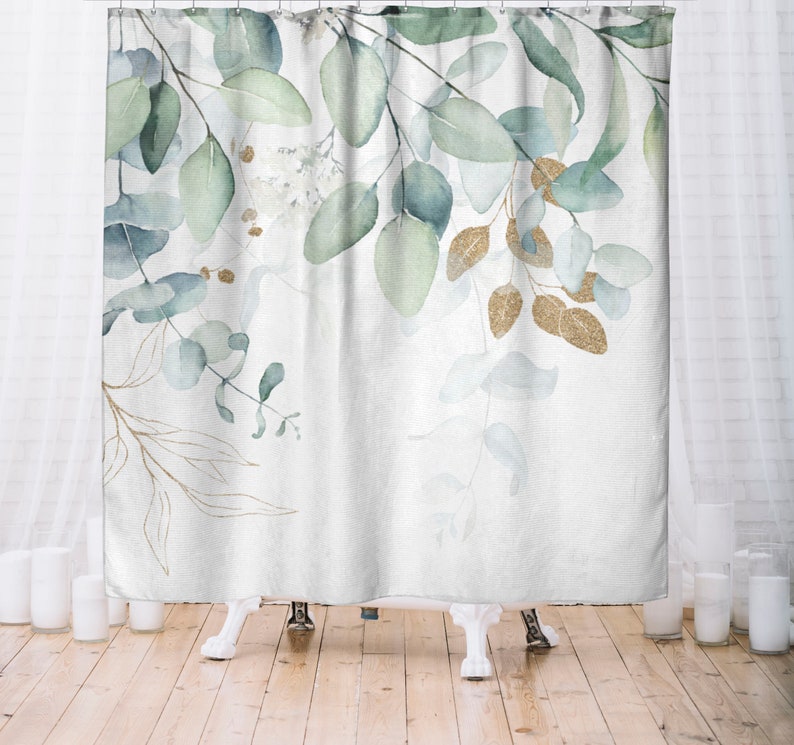 May include: A white shower curtain featuring a watercolor design of eucalyptus leaves in shades of green and blue, with accents of gold glitter. The leaves are arranged in a delicate, flowing pattern.