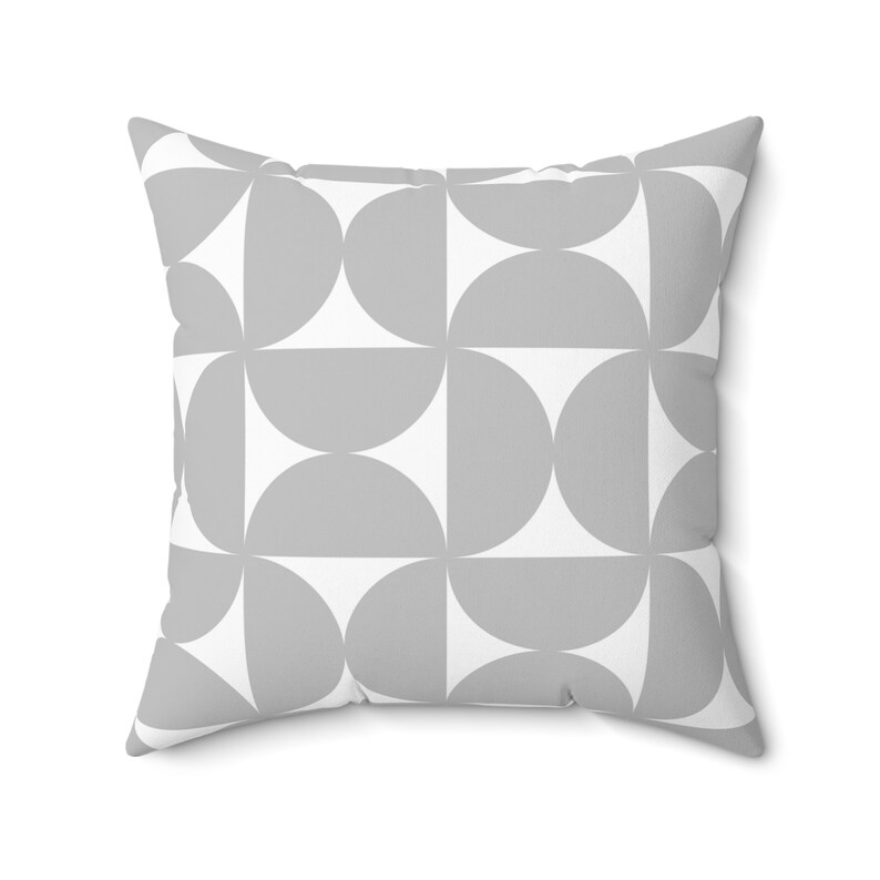 May include: Square throw pillow with a geometric pattern of gray semi-circles on a white background. The pillow has a soft, textured appearance and a modern design, suitable for home decor.