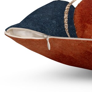 May include: A throw pillow with a zipper closure. The pillow features a geometric design with abstract shapes in shades of blue, orange, and gold.