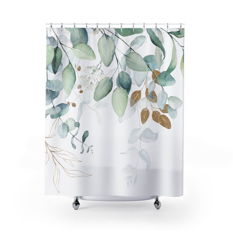 May include: White shower curtain with a watercolor design of green eucalyptus leaves and gold accents. The leaves are arranged in a cascading pattern, creating a natural and elegant look. The curtain hangs from a metal rod.