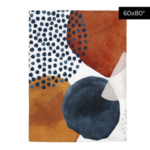 Puede incluir: Manta de tiro abstracta con fondo blanco y formas coloridas. Las formas son en tonos de azul, naranja y marr&oacute;n. La manta mide 60 pulgadas por 80 pulgadas.