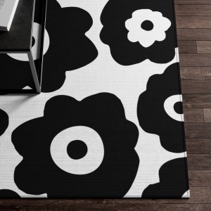 Peut inclure: Tapis de sol noir et blanc avec un motif r&eacute;p&eacute;titif de fleurs stylis&eacute;es. Les fleurs ont un design simple et moderne.