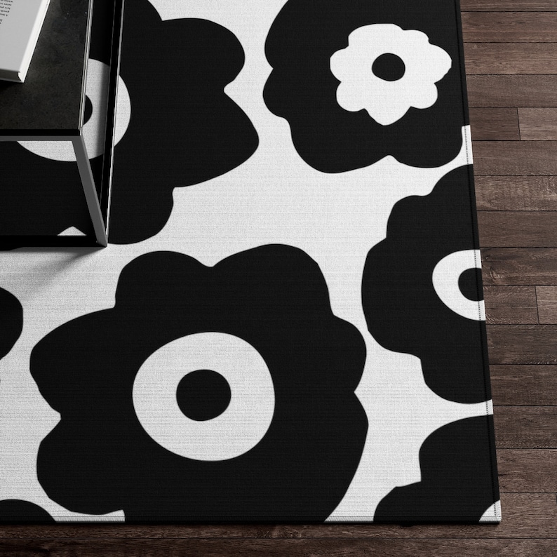 Peut inclure: Tapis de sol noir et blanc avec un motif r&eacute;p&eacute;titif de fleurs stylis&eacute;es. Les fleurs ont un design simple et moderne.