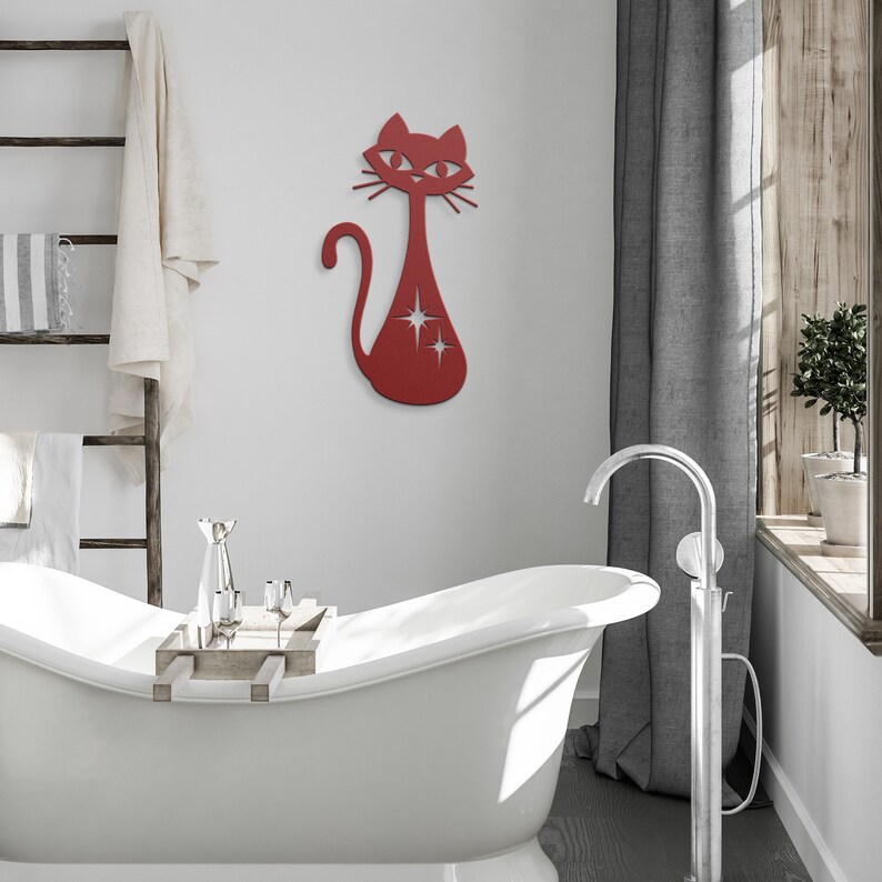 May include: Red metal cat wall decor with a starburst design. The cat is in a standing position with its tail curled around its body. The cat is mounted on a white wall above a white bathtub.