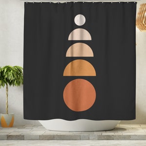 May include: Black shower curtain with a geometric design. The design features a series of stacked shapes in a vertical line: a white circle, two half-circles in beige, a half-circle in orange, and a large orange circle at the bottom. The curtain is hanging in front of a white bathtub.
