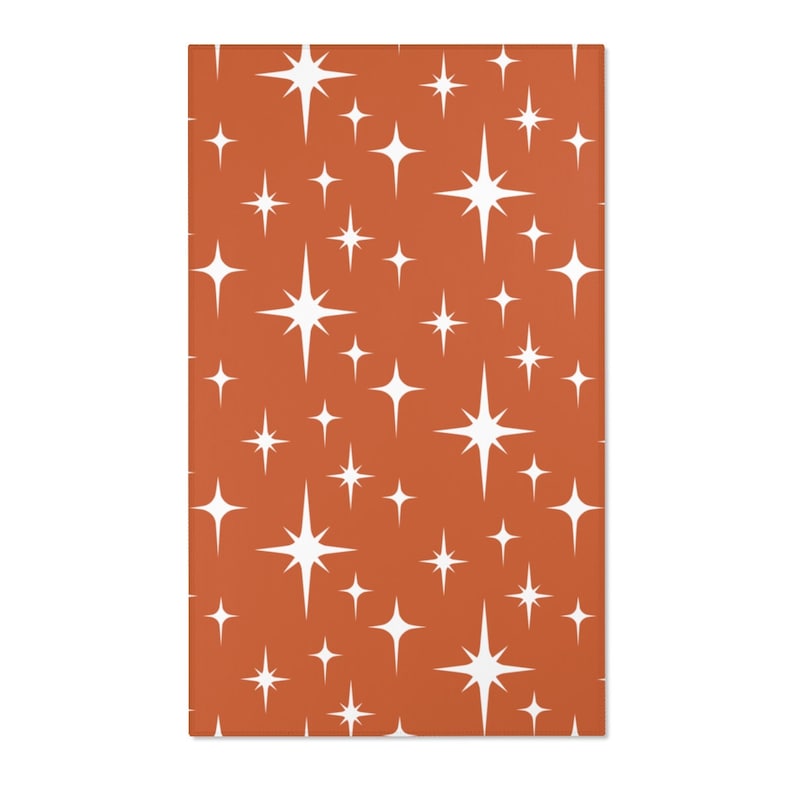 May include: A seamless pattern featuring white starbursts on a burnt orange background. The starbursts are of varying sizes and are arranged in a repeating pattern.