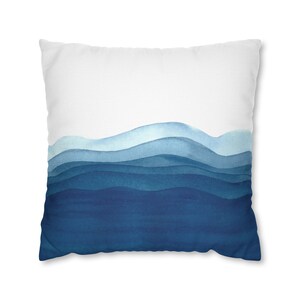 Puede incluir: Una almohada blanca con un dise&ntilde;o de acuarela azul de olas abstractas. Las olas est&aacute;n superpuestas en tonos de azul, de claro a oscuro.