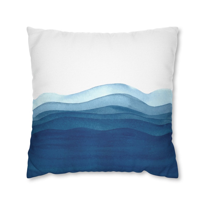 Puede incluir: Una almohada blanca con un dise&ntilde;o de acuarela azul de olas abstractas. Las olas est&aacute;n superpuestas en tonos de azul, de claro a oscuro.
