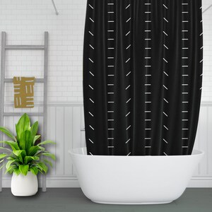 May include: Black shower curtain with a white geometric pattern. The curtain is hanging in a bathroom with a white bathtub.