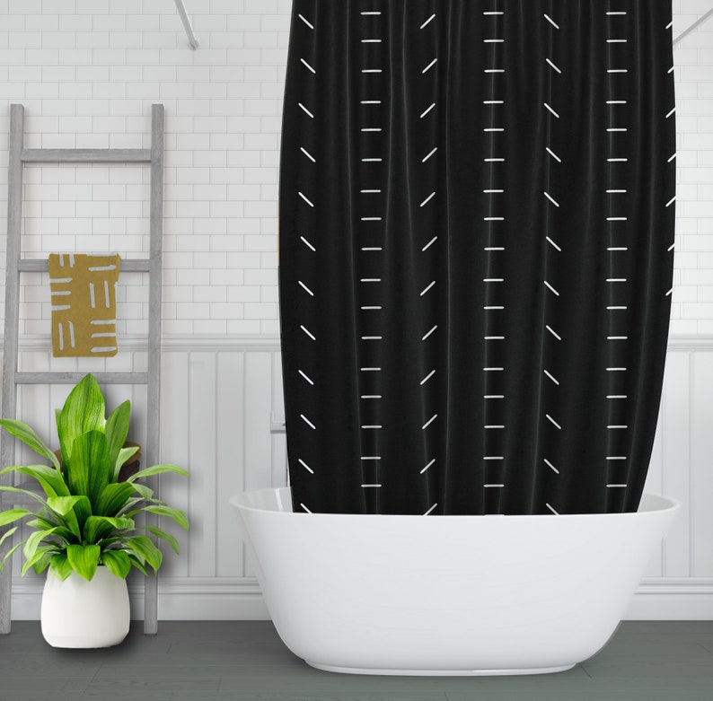 May include: Black shower curtain with a white geometric pattern. The curtain is hanging in a bathroom with a white bathtub.