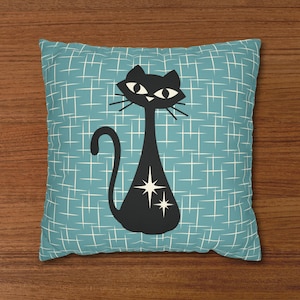 May include: A blue and white patterned throw pillow with a black silhouette of a cat with white stars on its body.