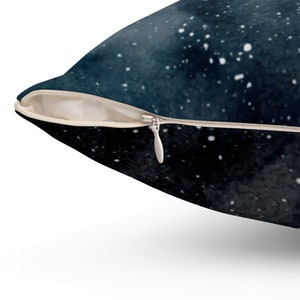 May include: A dark blue throw pillow with a white zipper closure. The pillow features a galaxy print with white stars on a dark blue background.