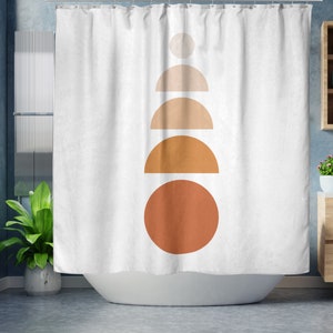 May include: White shower curtain with a minimalist design featuring a stack of geometric shapes in shades of beige and orange. The shapes include a circle, semi-circles, and a small circle at the top. The curtain is hanging in a bathroom setting.