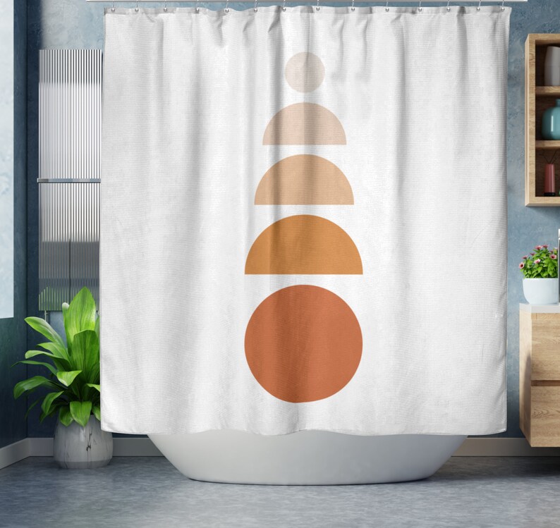 May include: White shower curtain with a minimalist design featuring a stack of geometric shapes in shades of beige and orange. The shapes include a circle, semi-circles, and a small circle at the top. The curtain is hanging in a bathroom setting.
