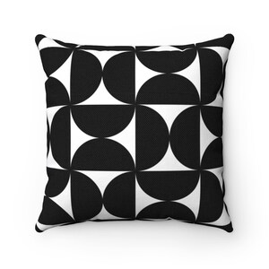 May include: Square throw pillow with a black and white geometric pattern. The design features a repeating pattern of black semi-circles and white squares. The pillow has a textured appearance and a solid white background.