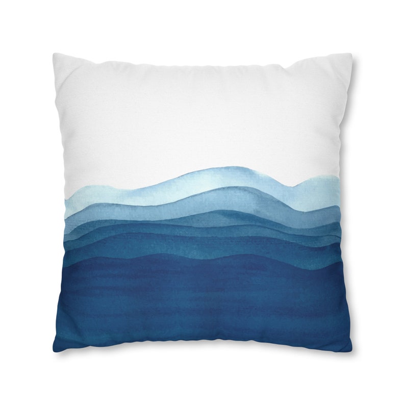 Puede incluir: Una almohada blanca con un dise&ntilde;o de acuarela azul de olas abstractas. Las olas est&aacute;n superpuestas en tonos de azul, de claro a oscuro.