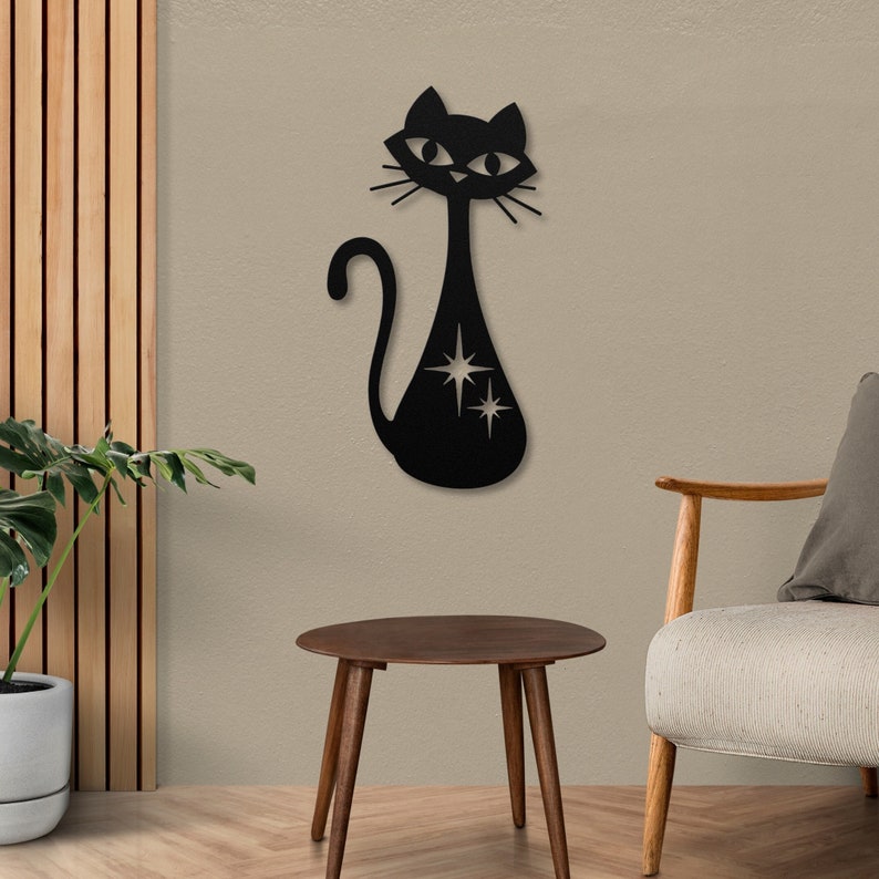 May include: Black metal wall decor featuring a stylized cat with a long tail and large eyes. The cat has a cutout design of stars on its body.