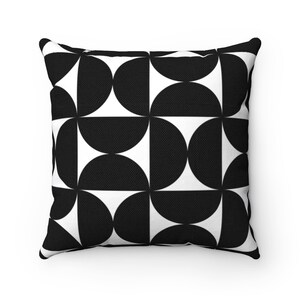 May include: Square throw pillow with a black and white geometric pattern. The design features a repeating pattern of black semi-circles against a white background. The pillow has a textured appearance and is likely made of fabric.